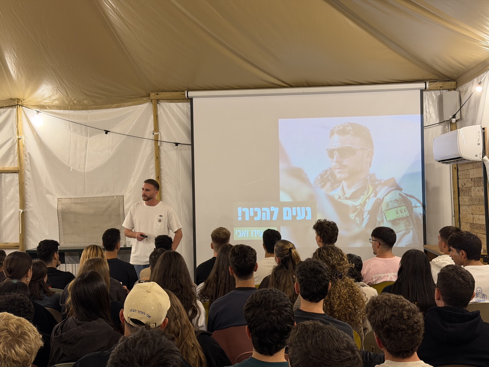 עידו זאבי על הבמה, ברקע שקופית 'נעים להכיר'